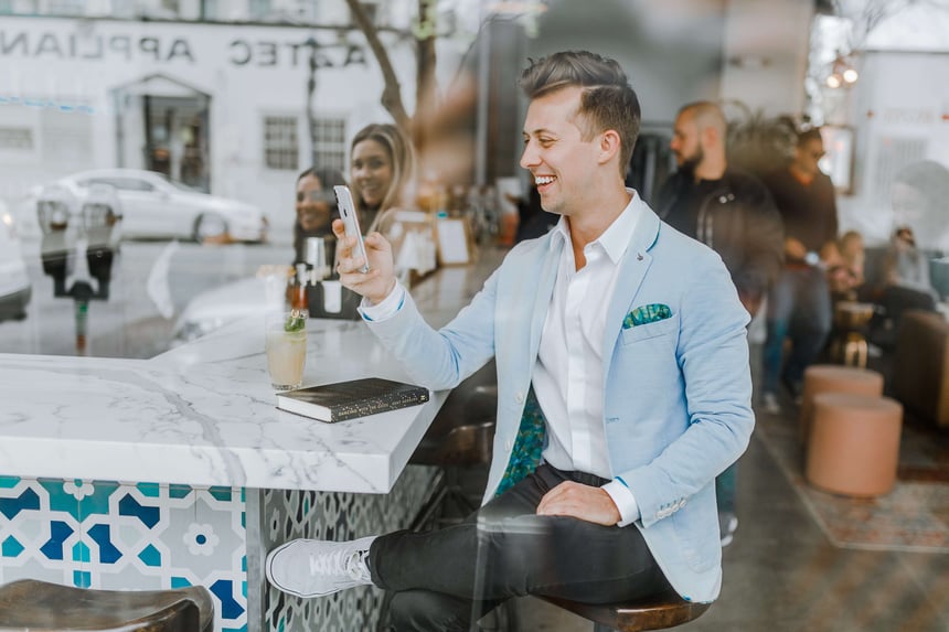 man sitting at a table and smiling at phone