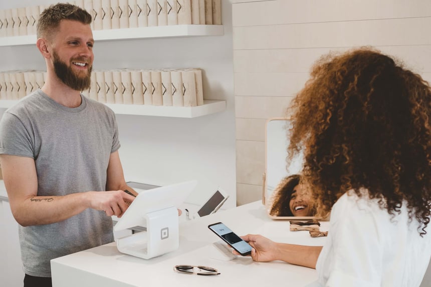 man and woman talking by a cash register 